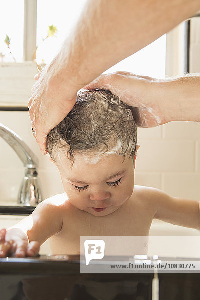 Vater wäscht seinen kleinen Sohn in der Spüle