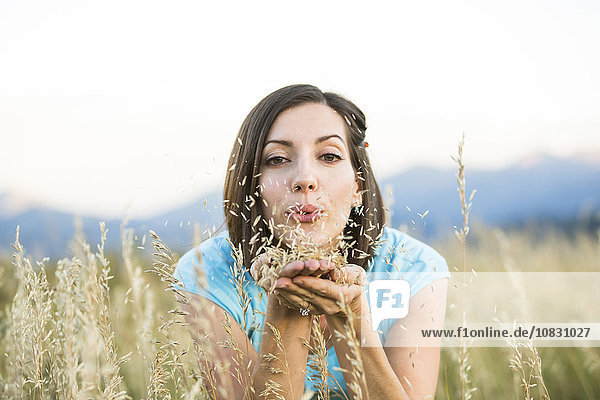 Kaukasische Frau bläst Samen auf einem Feld