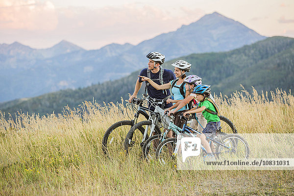 Kaukasische Familie fährt Mountainbike auf einem Feld