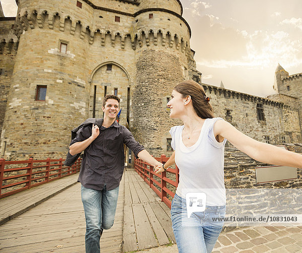Caucasian couple running at castle