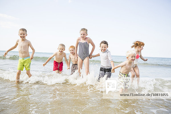 Kaukasische Kinder spielen in den Wellen am Strand