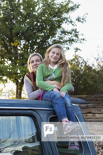 Caucasian mother and daughter hugging on truck roof