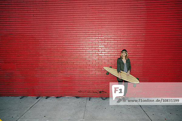 Caucasian woman holding skateboard on sidewalk