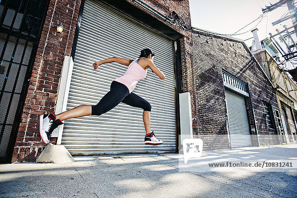 Mixed race woman running on sidewalk