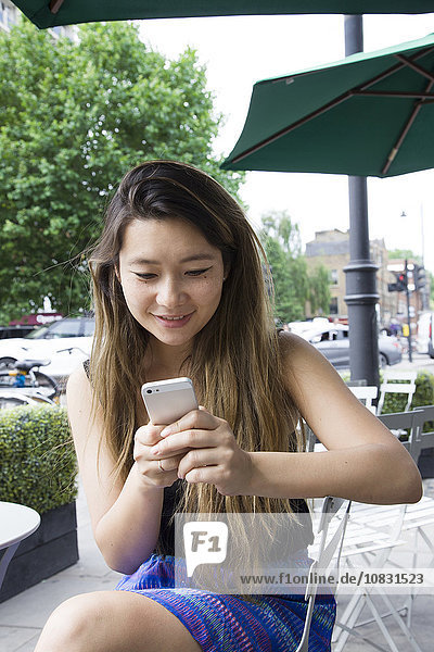 Asiatische Frau benutzt Mobiltelefon im Freien