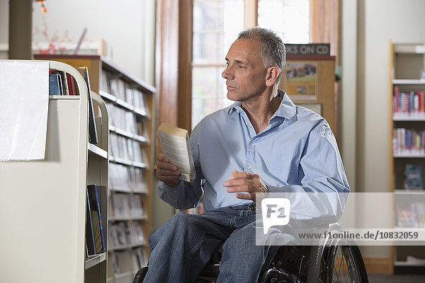 Kaukasischer Mann hält Buch in Bibliothek