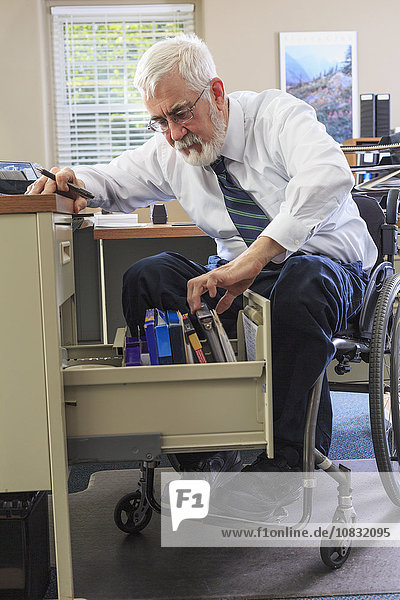 Caucasian businessman filing papers at desk