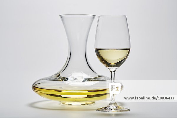 Glaskaraffe und ein Glas mit Weisswein auf weißem Hintergrund