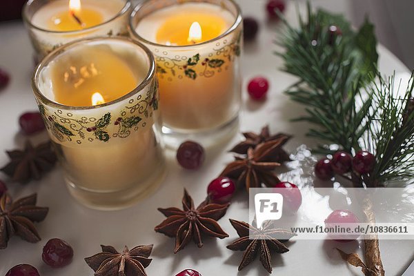 Drei Kerzen in Gläsern weihnachtlich dekoriert mit Moosbeeren & Sternanis