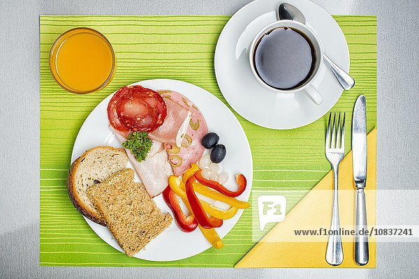 Frühstücksgedeck mit Brot, Wurst, Kaffee & Orangensaft Aufsicht - Stockfoto