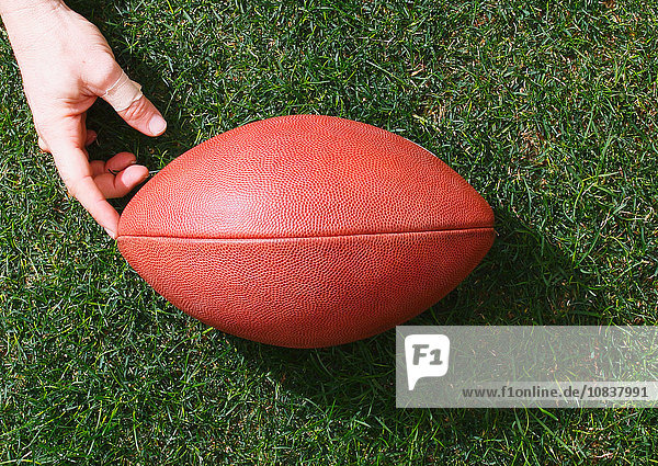 Man with American football ball on grass