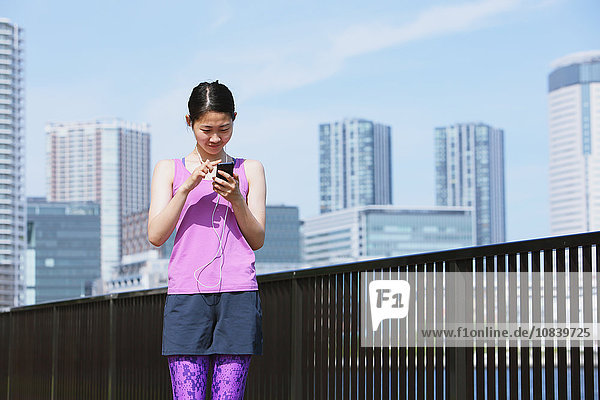 Young Japanese woman with smartphone before her run downtown Tokyo