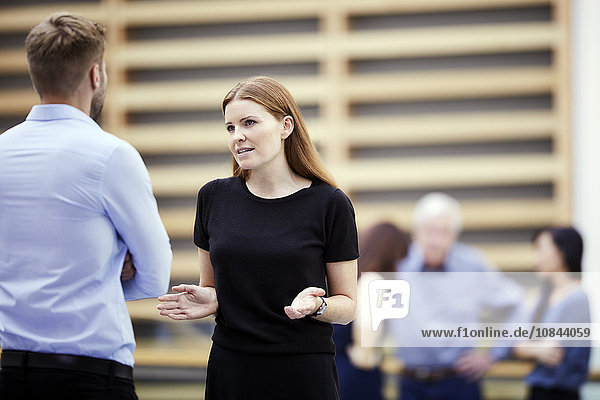 Businesswoman gesturing and talking to businessman in lobby