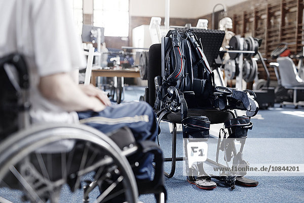 Mann im Rollstuhl in der Nähe von Physiotherapiegeräten