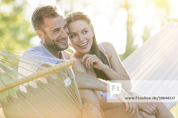Zärtliches junges Paar lächelnd in der Sommerhängematte