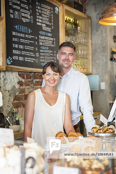 Portrait lächelndes Cafébesitzerpaar hinter der Theke
