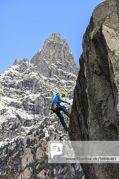 Climber on steep rock face in the background blue sky and peaks of the Alps  Masino Valley  Valtellina  Lombardy  Italy  Europe