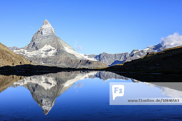Hikers admiring the Matterhorn reflected in Lake Stellisee  Zermatt  Canton of Valais  Pennine Alps  Swiss Alps  Switzerland  Europe