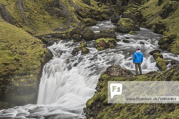 Tourist an einem Wasserfall auf dem Wanderweg oberhalb des Skogafoss-Wasserfalls  Skogar  Südregion (Sudurland)  Island  Polarregionen