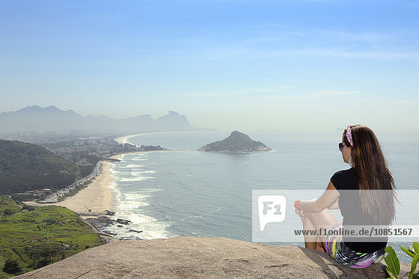 Ein junger Wanderer blickt von einem Aussichtspunkt auf die Strände Pontal und Recreio dos Bandeirantes in Barra da Tijuca  Rio de Janeiro  Brasilien  Südamerika