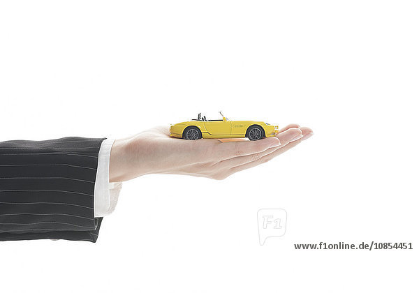 Modell eines gelben Sportwagens auf Frauenhand