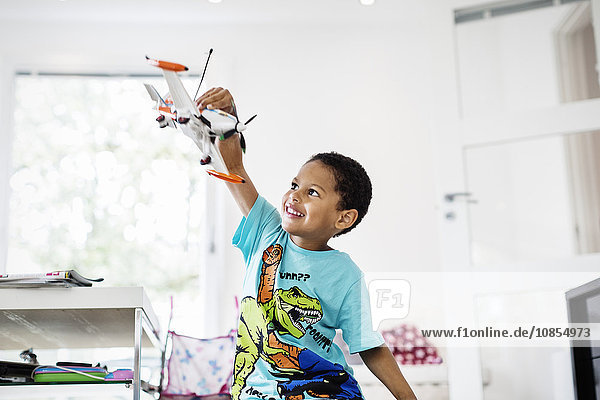 Happy boy playing with model airplane at home