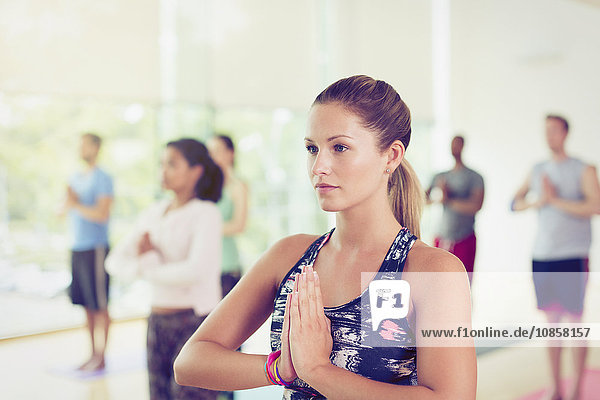 Focused woman with hands at prayer position in yoga class