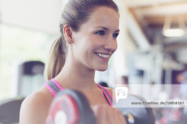 Close up lächelnde Frau tut Hantel Bizeps Locken im Fitnessstudio