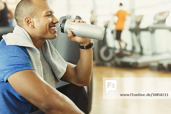 Smiling man drinking water at gym