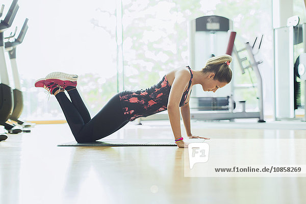 Woman doing push-ups on knees at gym