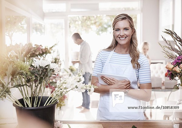Portrait smiling florist with digital tablet in flower shop