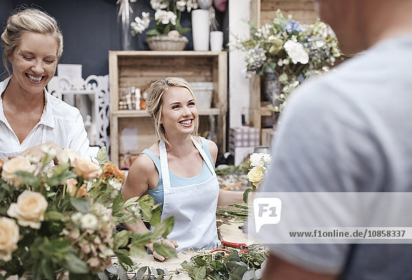 Floristen arrangieren Blumenstrauß und Kundengespräch im Blumenladen