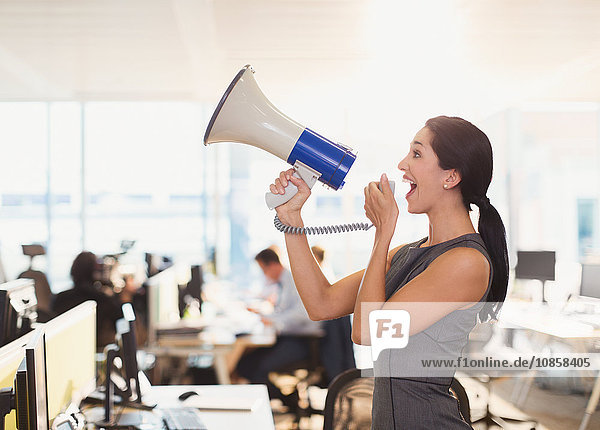 Exuberant businesswoman using megaphone in office