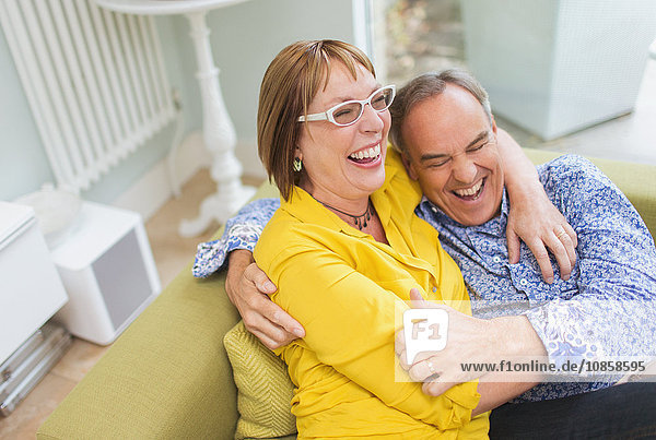 Mature couple laughing and hugging on sofa