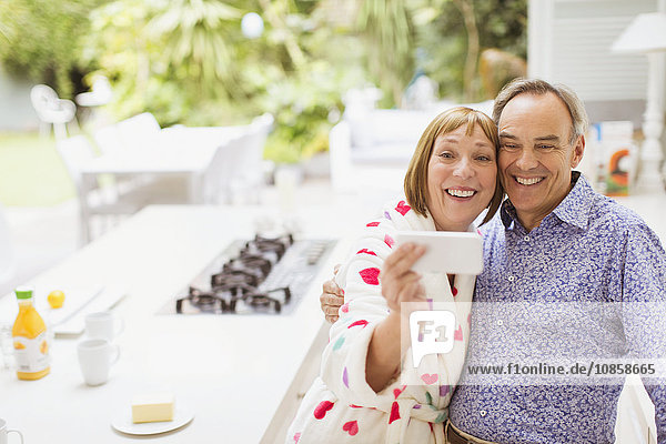 Smiling mature couple taking selfie in kitchen