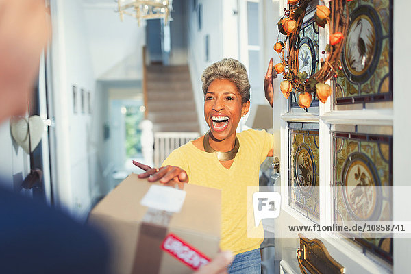 Enthusiastische Frau erhält Paketlieferung vor der Haustür