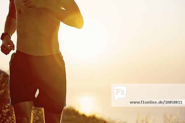 Bare chested man running at sunset