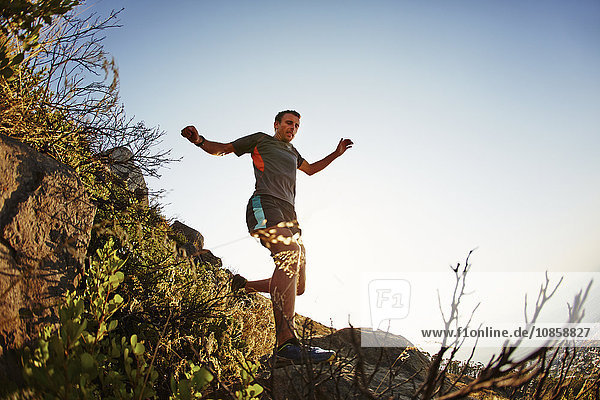 Male runner jumping and descending trail