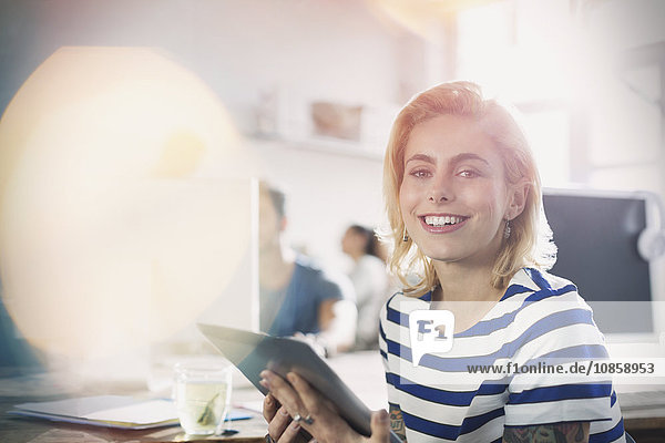 Portrait lächelnde junge kreative Geschäftsfrau mit digitalem Tablett im Büro
