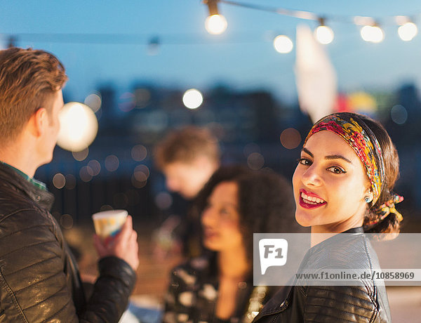 Portrait smiling young woman enjoying rooftop party at night