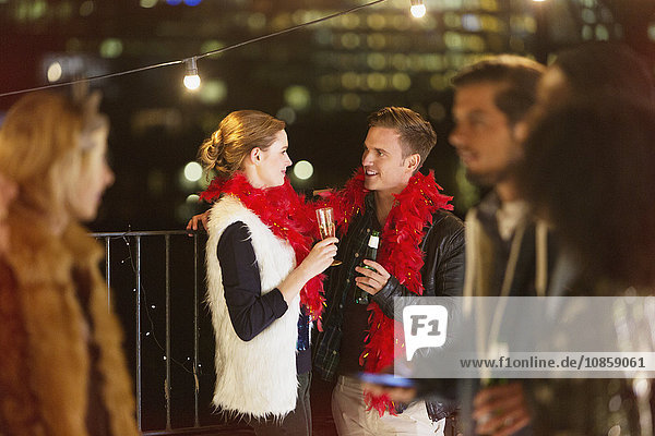 Young couple drinking champagne at nighttime rooftop party
