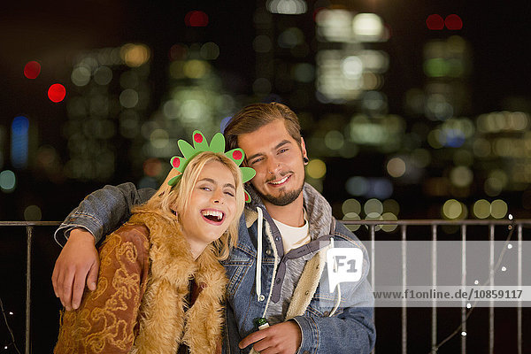 Portrait smiling young couple enjoying nighttime rooftop party