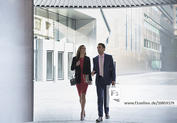 Corporate businessman and businesswoman walking outside building