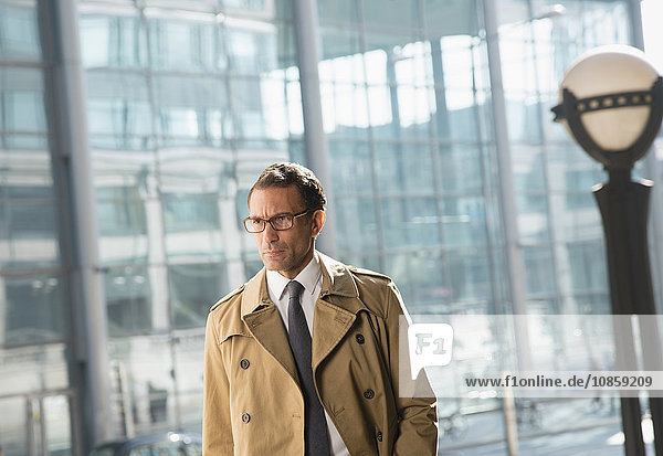 Corporate businessman in trench coat looking away