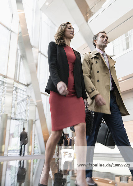 Corporate businessman and businesswoman walking in modern office lobby