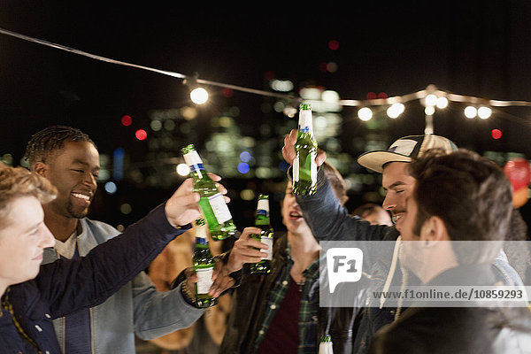 Young men drinking beer and dancing at rooftop party
