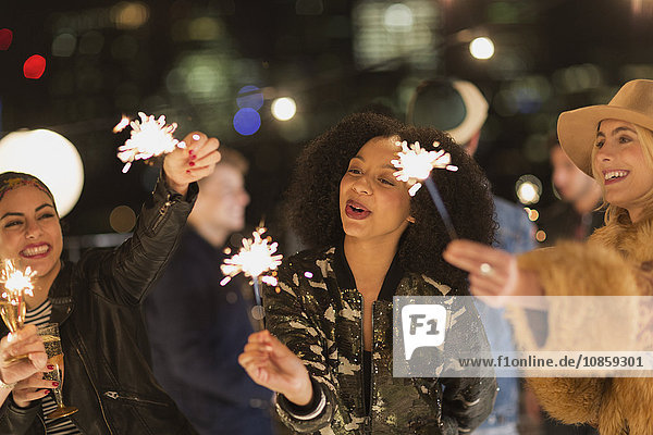 Young women waving sparklers at rooftop party