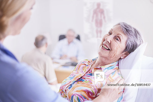 Doctor comforting smiling senior woman at checkup
