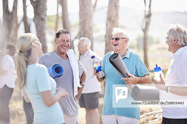 Yogalehrer im Gespräch mit älteren Männern nach dem Unterricht im Park