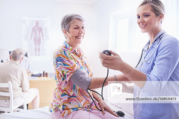 Arzt untersucht den Blutdruck der älteren Frau im Untersuchungszimmer